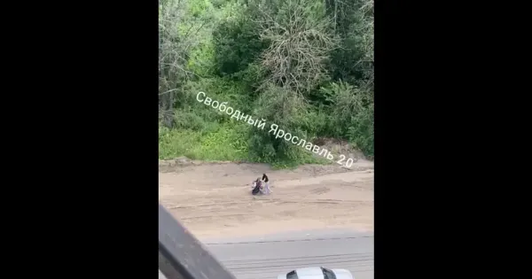 Женщина с детской коляской идет по обочине дороги, рядом проезжают автомобили